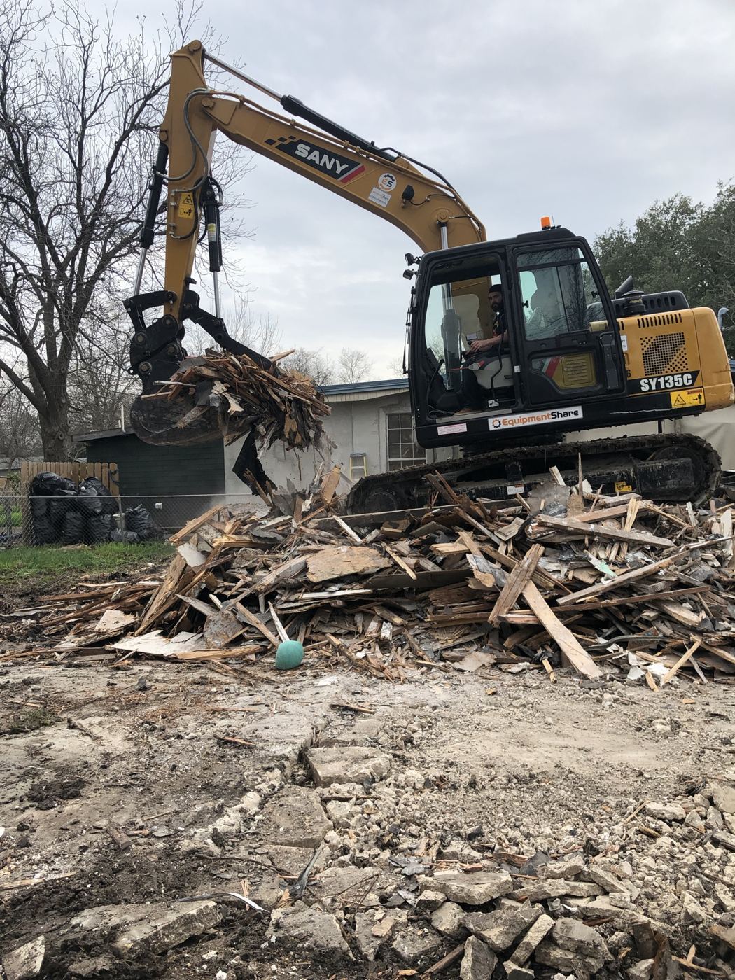 Excavator demolishing the existing house, Vargas Street condos design-build in Austin